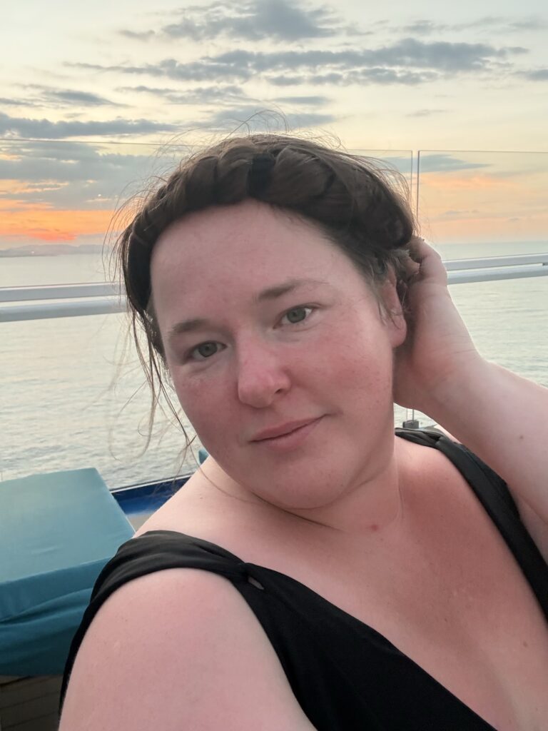 Bobbie JoEle, musician and travel writer, standing on an upper deck of a cruise ship